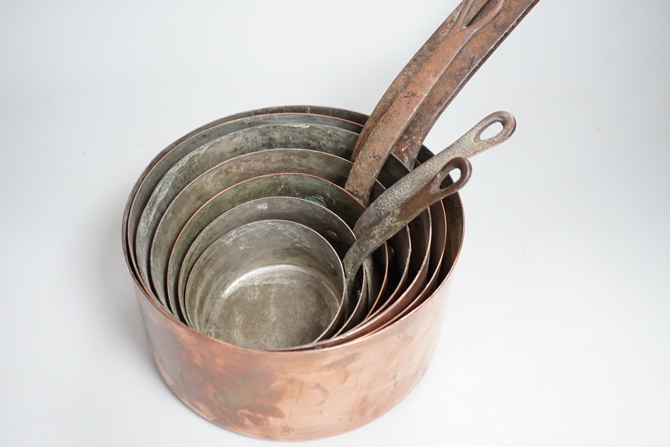 A graduated set of seven copper pans, the largest 47cm wide